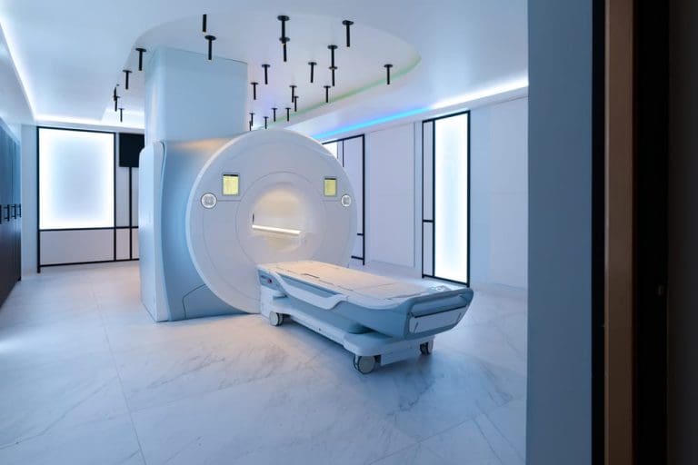 Modern MRI scanner in a bright, minimalist imaging room with a patient table extended toward the machine.