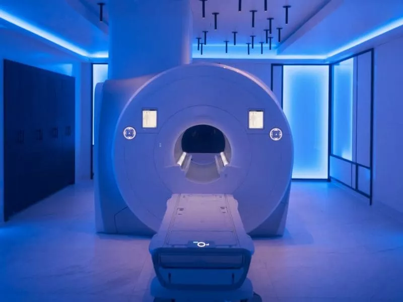 Empty MRI scanner in a modern imaging room with blue ambient lighting.